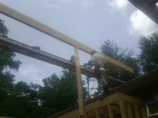 Carpenter setting a ridge beam over a new addition frame — Ice Dam Removal by Roofing Brothers in Cedar Falls