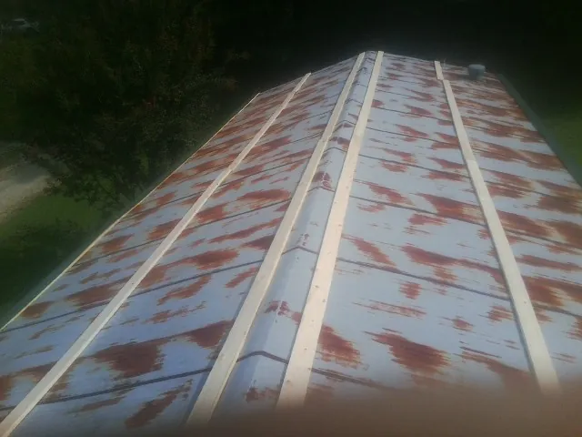 Rusted metal roof panels with new wood purlins before replacement — Storm Damage Roof Repair in Cedar Falls by Roofing Brothers