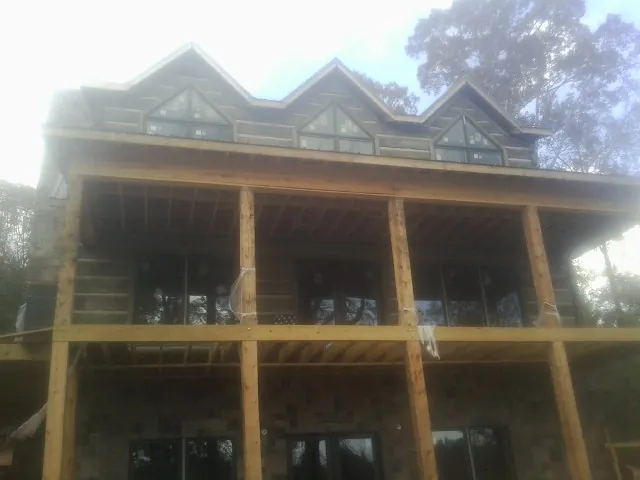Dormers and porch framing on a large log home under construction — Roof Coating work by our crew in Cedar Falls