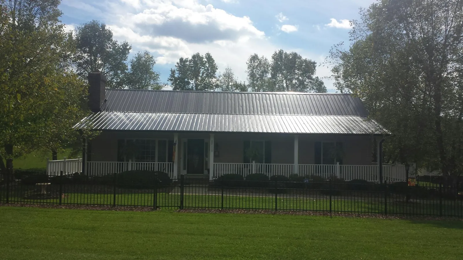 Gray metal roof on a brick ranch with a full width front porch — Gutter Guard Installation work by our crew in Cedar Falls